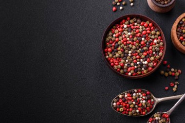 Spice allspice of different colors pink, white, green not ground in a wooden saucer on a dark concrete background