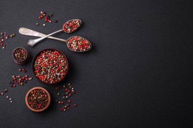 Spice allspice of different colors pink, white, green not ground in a wooden saucer on a dark concrete background