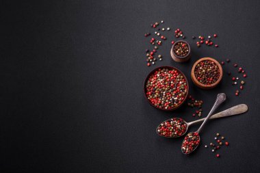 Spice allspice of different colors pink, white, green not ground in a wooden saucer on a dark concrete background