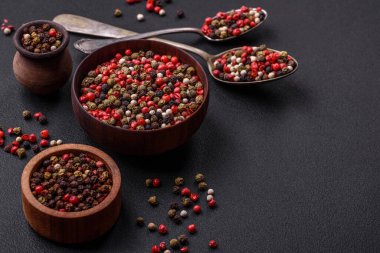 Spice allspice of different colors pink, white, green not ground in a wooden saucer on a dark concrete background