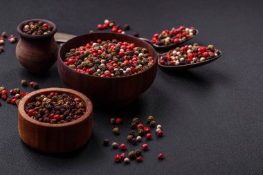 Spice allspice of different colors pink, white, green not ground in a wooden saucer on a dark concrete background