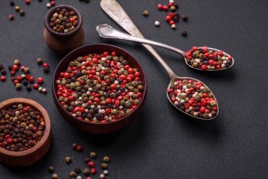 Spice allspice of different colors pink, white, green not ground in a wooden saucer on a dark concrete background