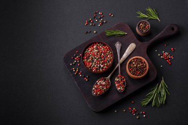 Spice allspice of different colors pink, white, green not ground in a wooden saucer on a dark concrete background