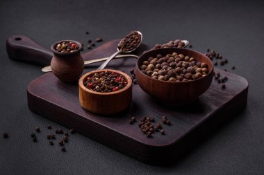 Spice allspice brown color not ground in a wooden saucer on a dark concrete background