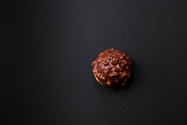 Delicious chocolate tart with nuts on a black ceramic plate on a dark concrete background