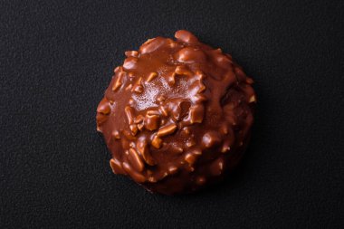 Delicious chocolate tart with nuts on a black ceramic plate on a dark concrete background