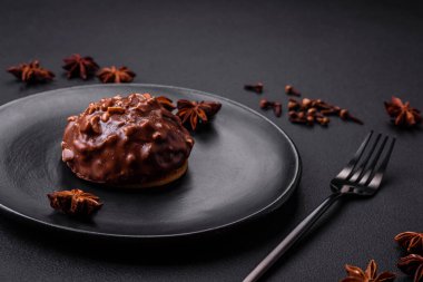 Delicious chocolate tart with nuts on a black ceramic plate on a dark concrete background