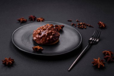 Delicious chocolate tart with nuts on a black ceramic plate on a dark concrete background