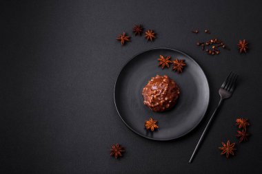Delicious chocolate tart with nuts on a black ceramic plate on a dark concrete background
