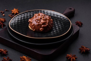 Delicious chocolate tart with nuts on a black ceramic plate on a dark concrete background