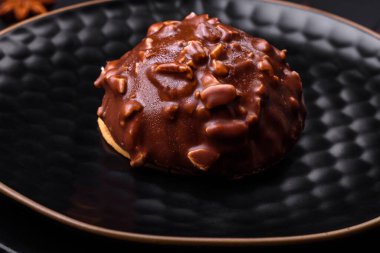 Delicious chocolate tart with nuts on a black ceramic plate on a dark concrete background