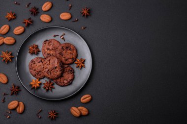 Delicious chocolate cookies with nuts on a black ceramic plate on a dark concrete background