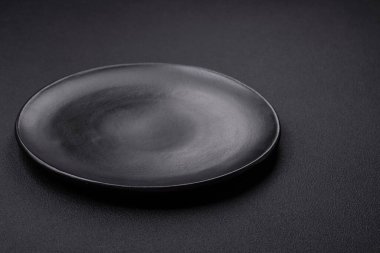 Empty ceramic round plate on dark textured concrete background. Cutlery, preparation for dinner
