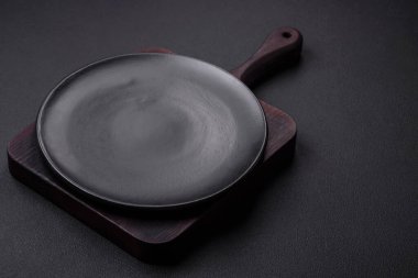 Empty ceramic round plate on dark textured concrete background. Cutlery, preparation for dinner