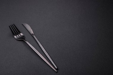 Metal kitchen knife and fork on a dark textured concrete background. Cutlery, preparation for dinner