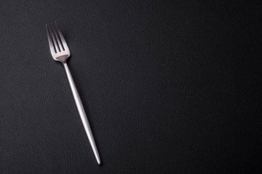 Metal kitchen fork on a dark textured concrete background. Cutlery, preparation for dinner