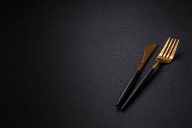 Metal kitchen knife and fork on a dark textured concrete background. Cutlery, preparation for dinner