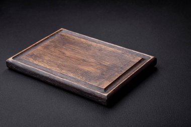 Empty wooden cutting board on dark textured concrete background. Cutlery, preparation for dinner