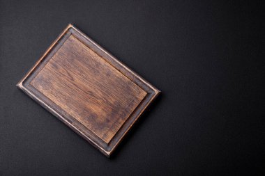 Empty wooden cutting board on dark textured concrete background. Cutlery, preparation for dinner