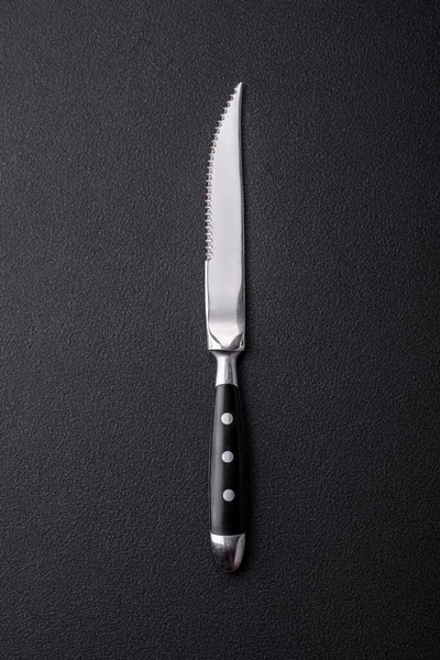 Metal kitchen knife on a dark textured concrete background. Cutlery, preparation for dinner