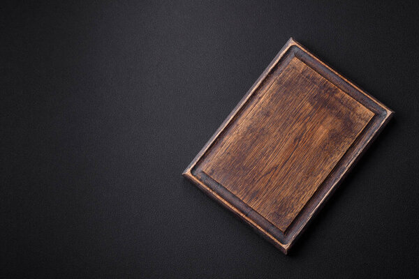 Empty wooden cutting board on dark textured concrete background. Cutlery, preparation for dinner