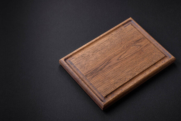 Empty wooden cutting board on dark textured concrete background. Cutlery, preparation for dinner
