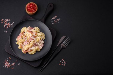 Siyah seramik tabakta koyu beton zemin üzerinde pastırmalı ve parmesan peynirli lezzetli makarna. İtalyan mutfağı
