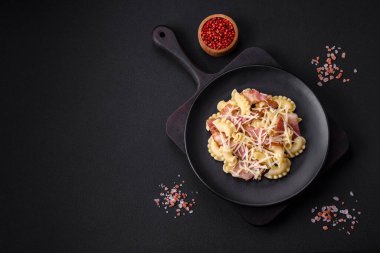 Siyah seramik tabakta koyu beton zemin üzerinde pastırmalı ve parmesan peynirli lezzetli makarna. İtalyan mutfağı