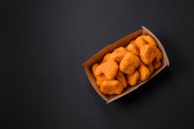 Delicious fresh crispy chicken nuggets on a dark concrete background. Unhealthy food, fast food