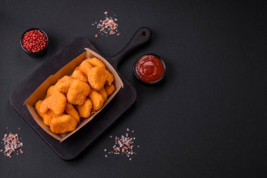 Delicious fresh crispy chicken nuggets on a dark concrete background. Unhealthy food, fast food