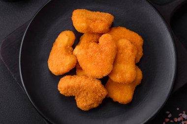 Delicious fresh crispy chicken nuggets on a dark concrete background. Unhealthy food, fast food