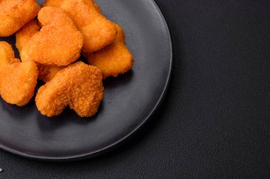 Delicious fresh crispy chicken nuggets on a dark concrete background. Unhealthy food, fast food