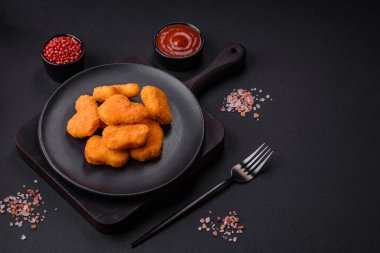 Delicious fresh crispy chicken nuggets on a dark concrete background. Unhealthy food, fast food