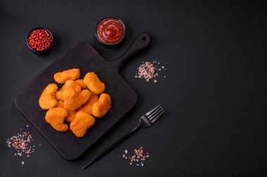 Delicious fresh crispy chicken nuggets on a dark concrete background. Unhealthy food, fast food