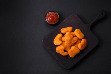 Delicious fresh crispy chicken nuggets on a dark concrete background. Unhealthy food, fast food