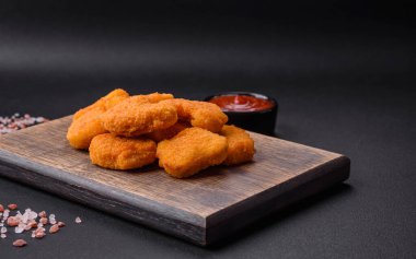 Delicious fresh crispy chicken nuggets on a dark concrete background. Unhealthy food, fast food