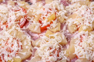 A dish consisting of meat, tomatoes, pineapple, cheese, spices and herbs on parchment on a baking sheet. Preparing food for baking in the oven