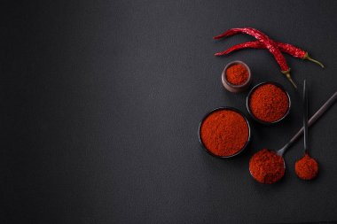 Spice smoked paprika in the form of powder in bowls and spoons on a dark concrete background. Asian cuisine ingredients