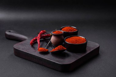 Spice smoked paprika in the form of powder in bowls and spoons on a dark concrete background. Asian cuisine ingredients
