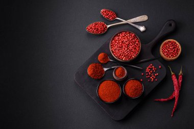 Spice smoked paprika in the form of powder in bowls and spoons on a dark concrete background. Asian cuisine ingredients