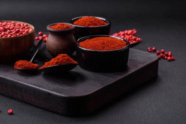 Spice smoked paprika in the form of powder in bowls and spoons on a dark concrete background. Asian cuisine ingredients