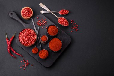 Spice smoked paprika in the form of powder in bowls and spoons on a dark concrete background. Asian cuisine ingredients