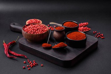 Spice smoked paprika in the form of powder in bowls and spoons on a dark concrete background. Asian cuisine ingredients
