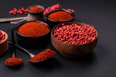 Spice smoked paprika in the form of powder in bowls and spoons on a dark concrete background. Asian cuisine ingredients