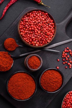 Spice smoked paprika in the form of powder in bowls and spoons on a dark concrete background. Asian cuisine ingredients