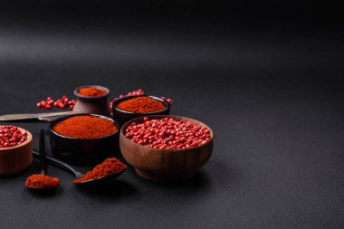Spice smoked paprika in the form of powder in bowls and spoons on a dark concrete background. Asian cuisine ingredients