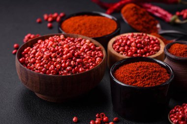 Spice smoked paprika in the form of powder in bowls and spoons on a dark concrete background. Asian cuisine ingredients