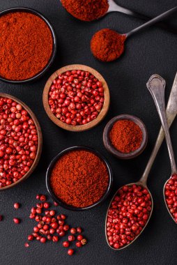 Spice smoked paprika in the form of powder in bowls and spoons on a dark concrete background. Asian cuisine ingredients