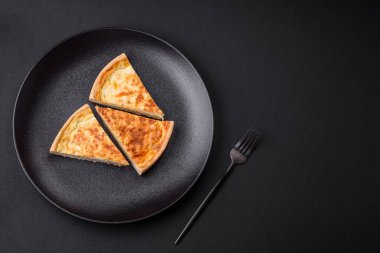 Beautiful delicious quiche pie with four types of cheese with spices and herbs on a dark concrete background