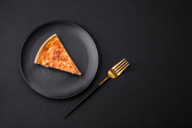 Beautiful delicious quiche pie with four types of cheese with spices and herbs on a dark concrete background